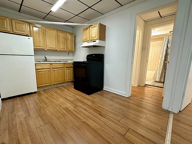 a kitchen with granite countertop wooden floors and white stainless steel appliances