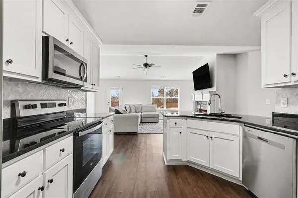 a kitchen with stainless steel appliances white cabinets a sink and a stove