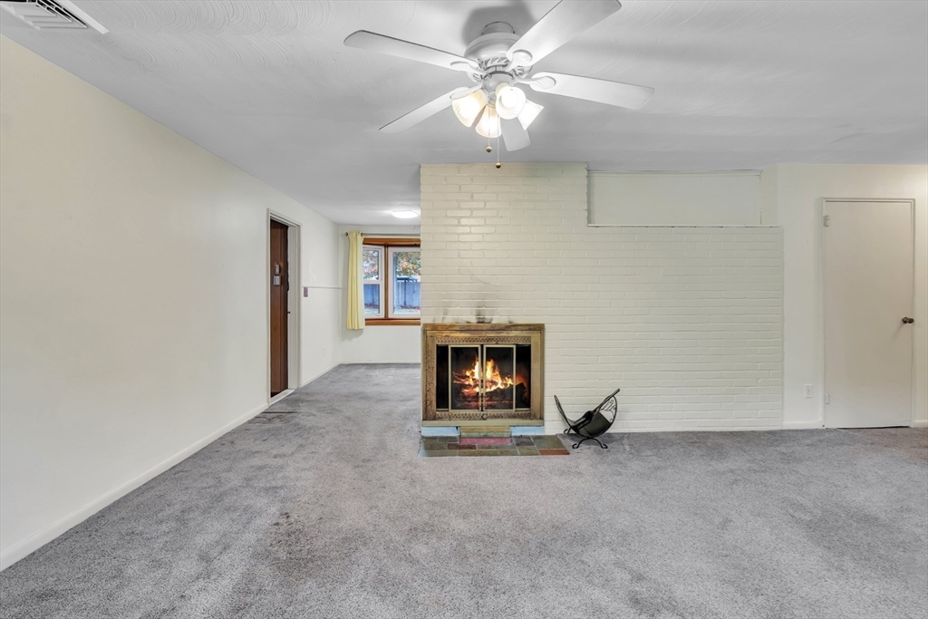 15 Fairbrook Road Framingham, MA 01701 - Photo 6 of 28 an empty room with a fireplace and fan
