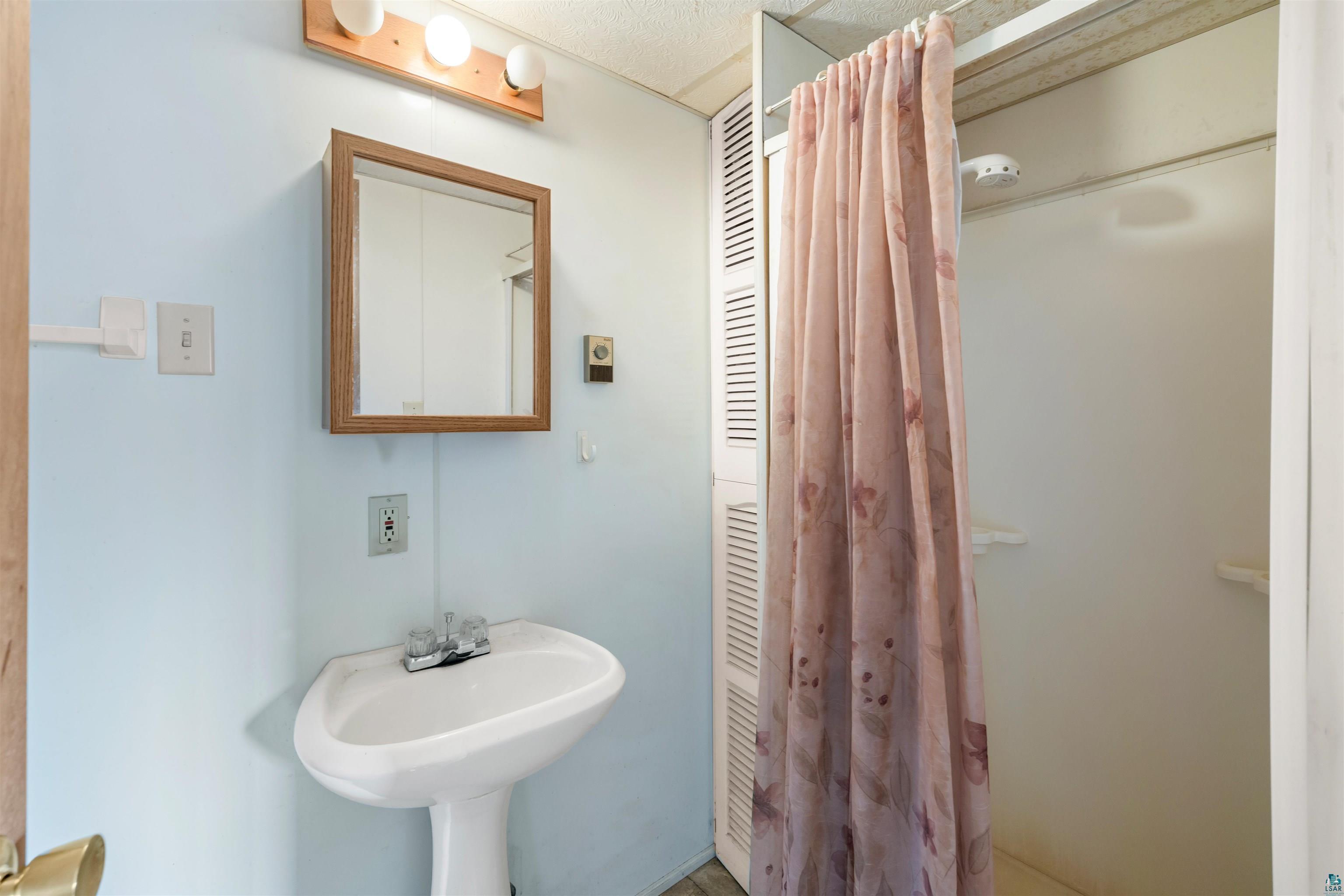 11574 Town Line Road Hibbing, MN 55746 - Photo 20 of 41 Bathroom featuring a pedestal sink, wall-mounted mirror, and a built-in shower stall