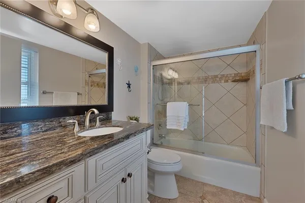 a bathroom with a granite countertop sink a toilet and shower