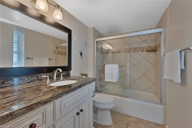 a bathroom with a granite countertop sink a toilet and shower