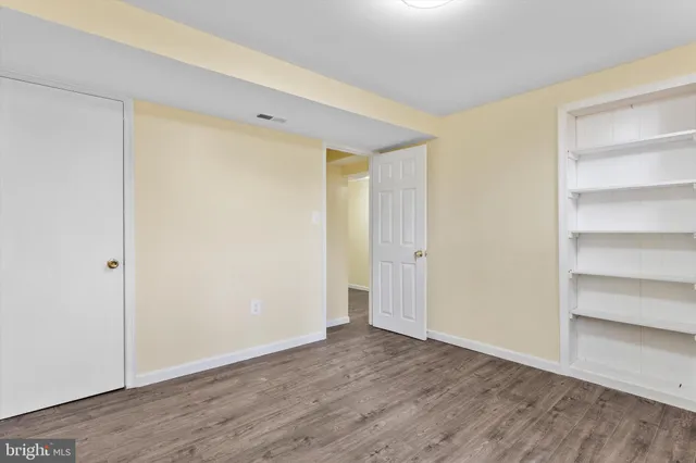 a view of an empty room with wooden floor and closet