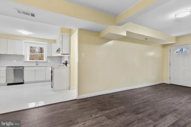 a view of a kitchen with white cabinets and wooden floor
