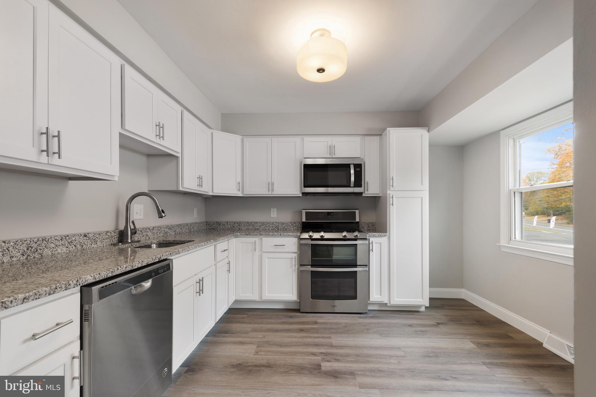 243 Jackson Road Mantua, NJ 08051 - Photo 4 of 18 a kitchen with stainless steel appliances granite countertop a stove a sink dishwasher and a microwave oven with white cabinets