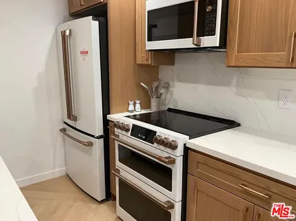 a kitchen with granite countertop white cabinets and white appliances
