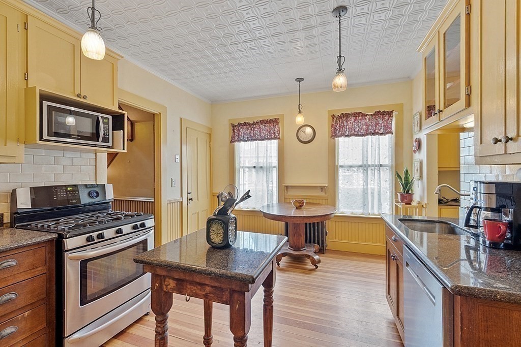 39 Maple Street Stoneham, MA 02180 - Photo 20 of 40 a kitchen with stainless steel appliances kitchen island granite countertop a stove a sink and a microwave