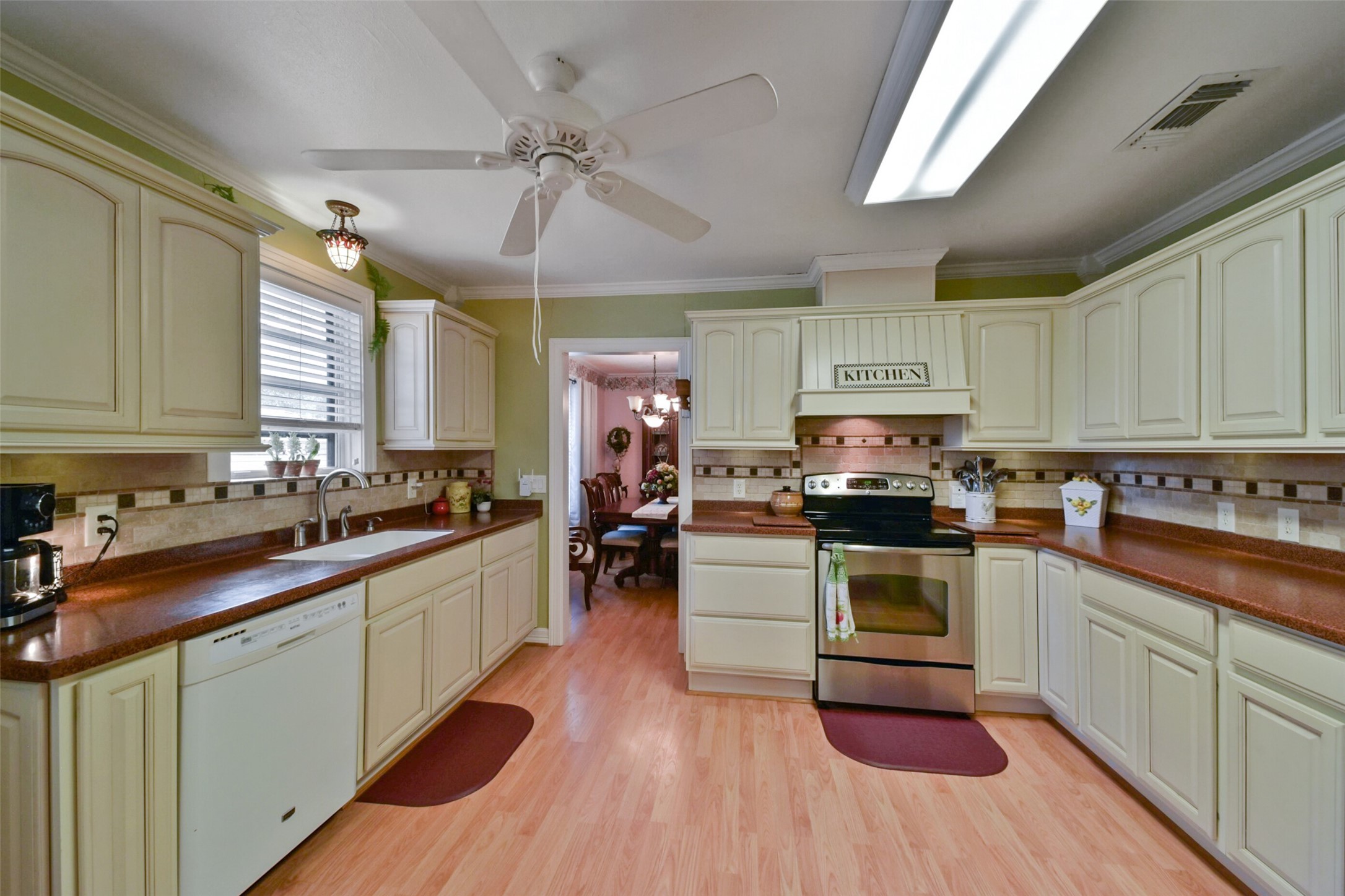 13710 Mueck Road Needville, TX 77461 - Photo 16 of 42 Discover a bright, spacious kitchen featuring cream cabinetry, wood countertops, and a stylish tile backsplash. Equipped with modern appliances, ample storage, and a ceiling fan, it seamlessly opens to a dining area. Enjoy abundant natural light from the skylight.