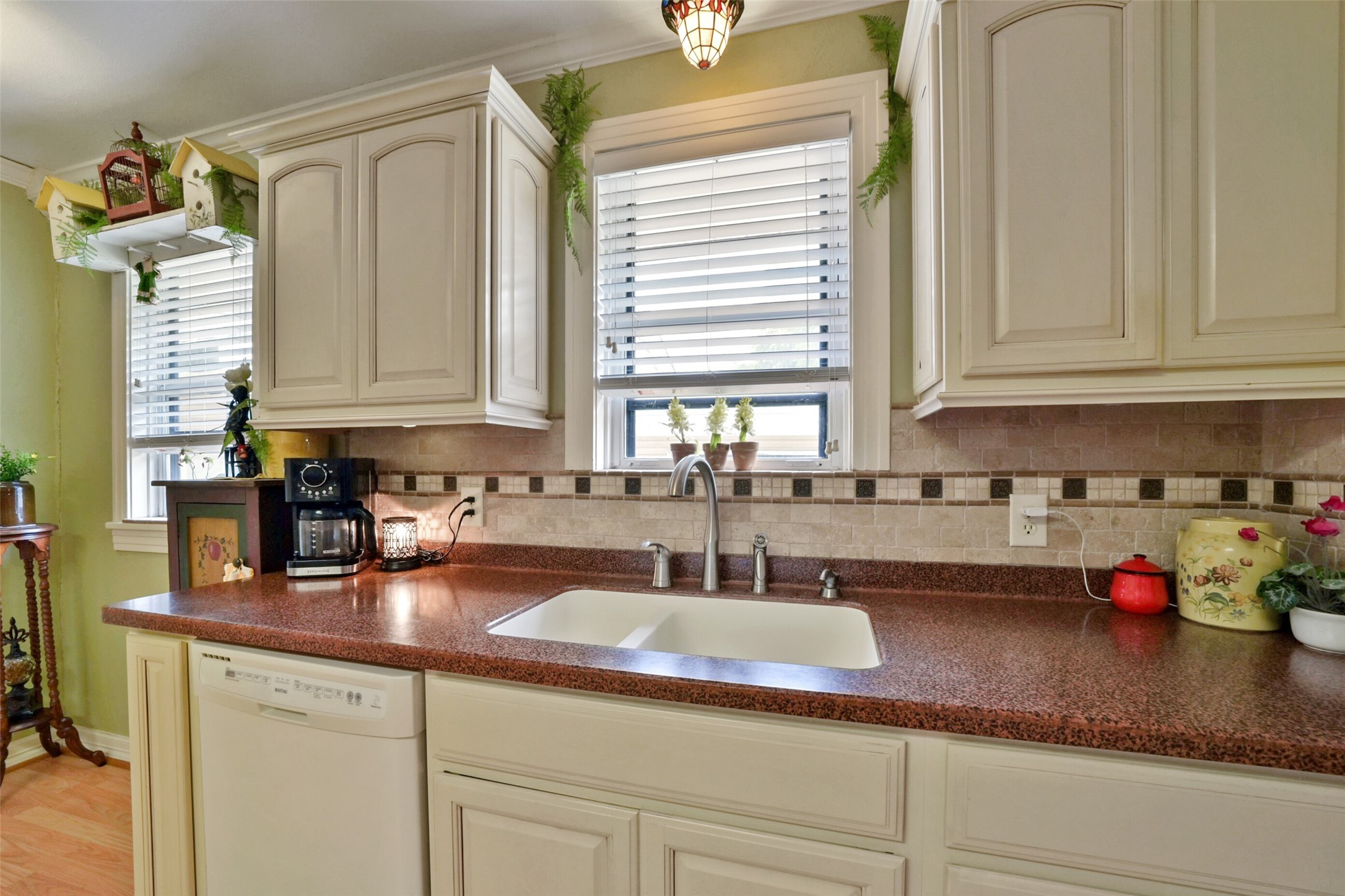 13710 Mueck Road Needville, TX 77461 - Photo 17 of 42 This is a cozy kitchen featuring cream-colored cabinetry, granite countertops with a tiled backsplash, under-cabinet lighting, and a window over the sink providing natural light.