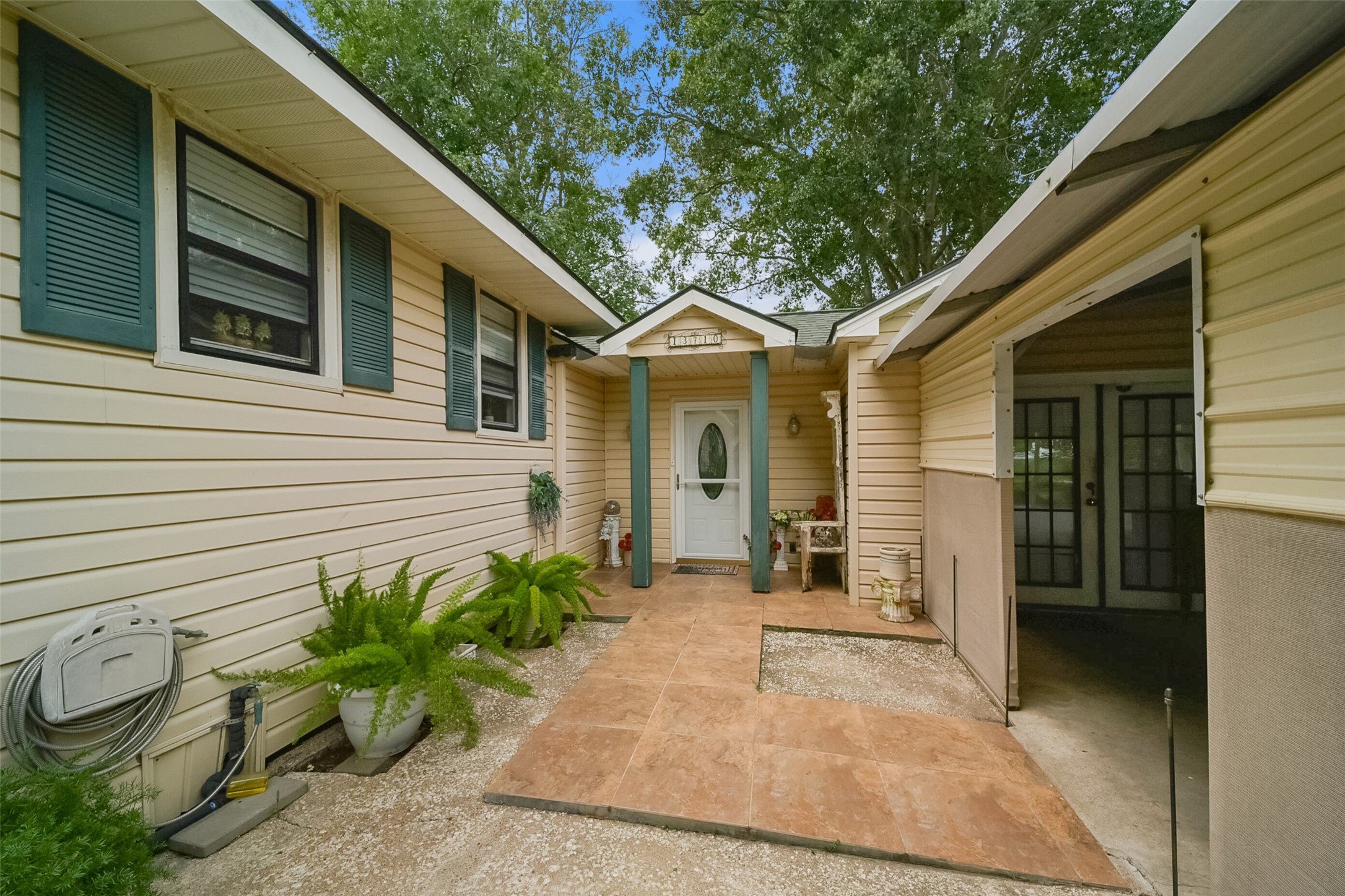 13710 Mueck Road Needville, TX 77461 - Photo 5 of 42 Cozy single-story home with charming beige siding and a welcoming covered entryway. Enjoy the convenience of a carport and the tranquility provided by mature, shade-giving trees. Simple yet tasteful landscaping enhances the curb appeal.