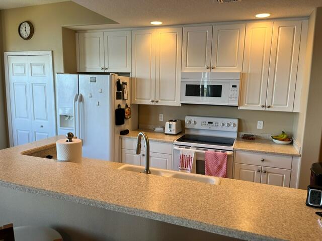 6828 Toland Drive, Unit 302 Melbourne, FL 32940 - Photo 11 of 45 a kitchen with stainless steel appliances granite countertop a sink a stove and a refrigerator