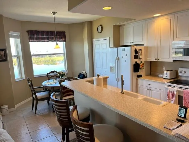a kitchen with stainless steel appliances sink refrigerator dining table and chairs