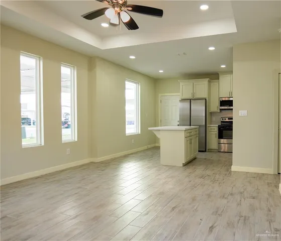 a view of an empty room with a window and kitchen view