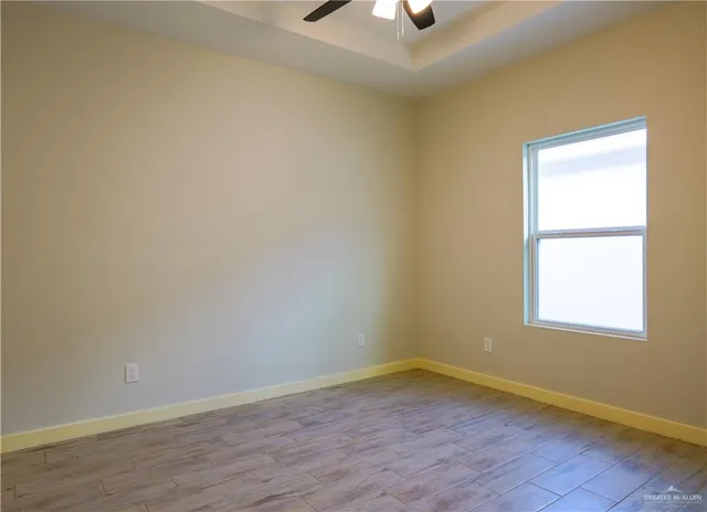 an empty room with a window and a ceiling fan