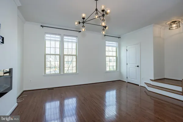 a large kitchen with stainless steel appliances kitchen island granite countertop a stove a sink a refrigerator and white cabinets with wooden floor