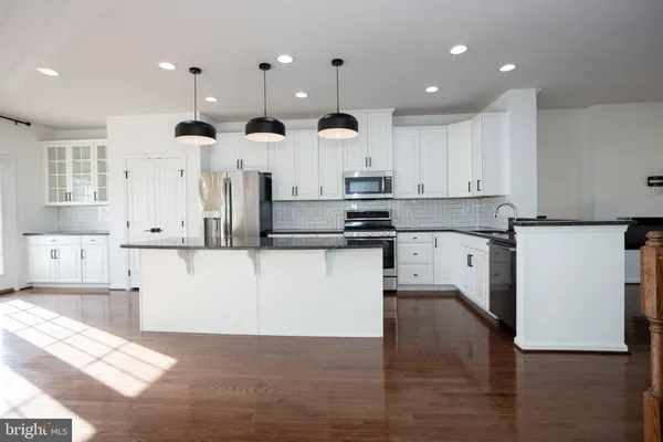a kitchen with stainless steel appliances kitchen island a refrigerator and a view of living room