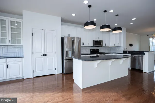a kitchen with stainless steel appliances kitchen island granite countertop wooden floors and cabinets