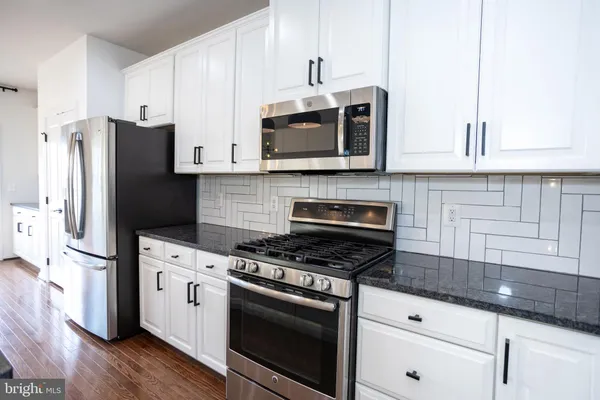 a kitchen with stainless steel appliances granite countertop a stove top oven a sink a window and living room view