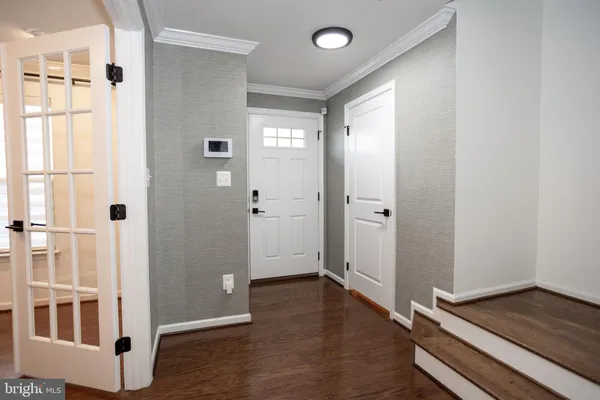 a view of a hallway with wooden floor and a bathroom