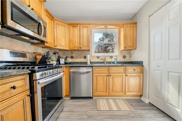 a kitchen with stainless steel appliances granite countertop a stove a sink and a microwave