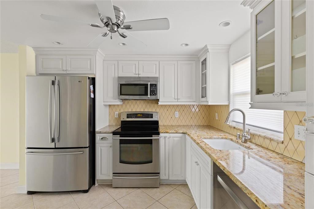 4775 Cove Circle, Unit 202 St. Petersburg, FL 33708 - Photo 6 of 19 a kitchen with a refrigerator sink and white cabinets