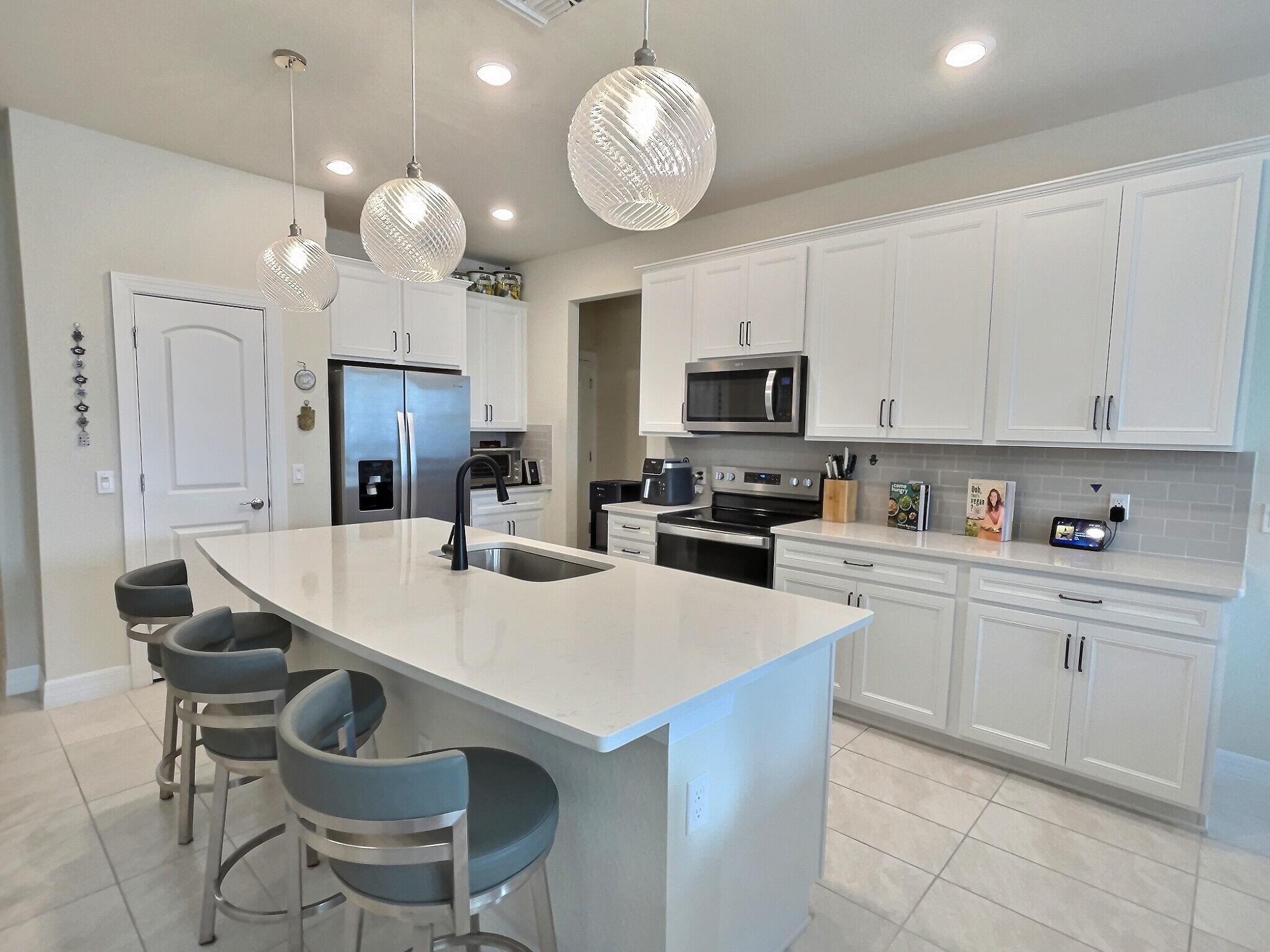 4829 Chantilly Road Lake Worth, FL 33467 - Photo 2 of 31 a kitchen with granite countertop a sink a stove a refrigerator and white cabinets with wooden floor