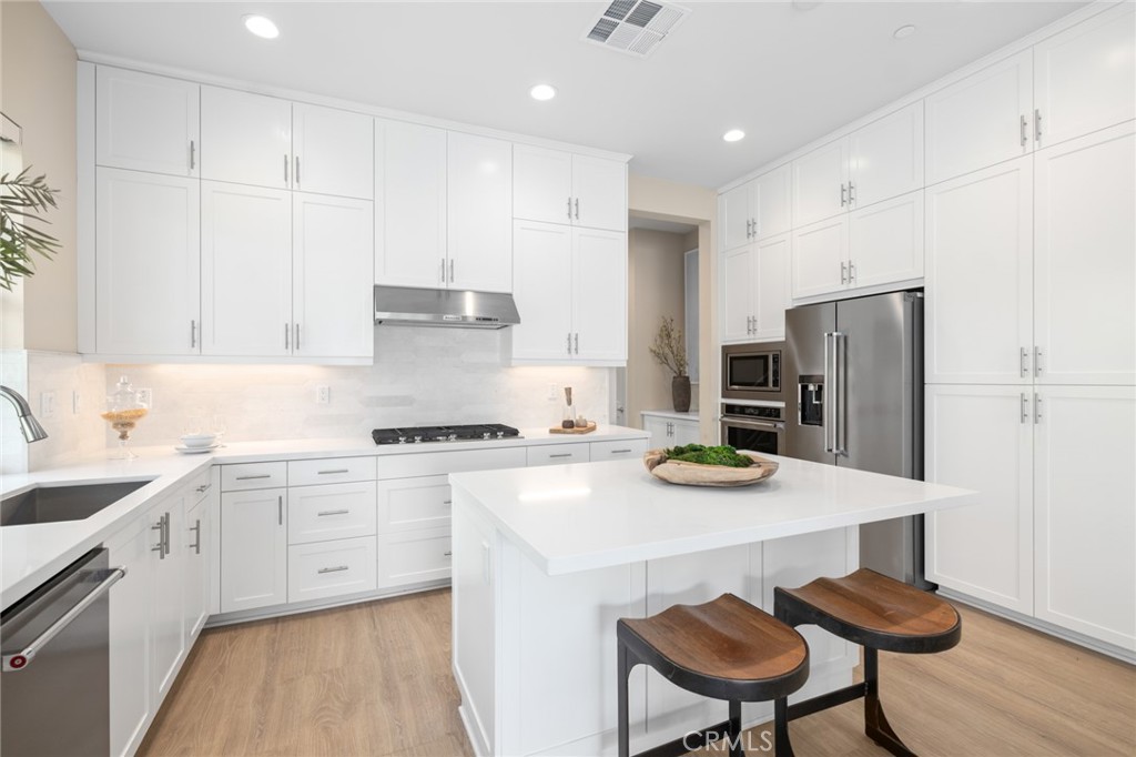 352 Novel Irvine, CA 92618 - Photo 12 of 75 a kitchen with stainless steel appliances granite countertop a sink a stove a refrigerator and white cabinets with wooden floor