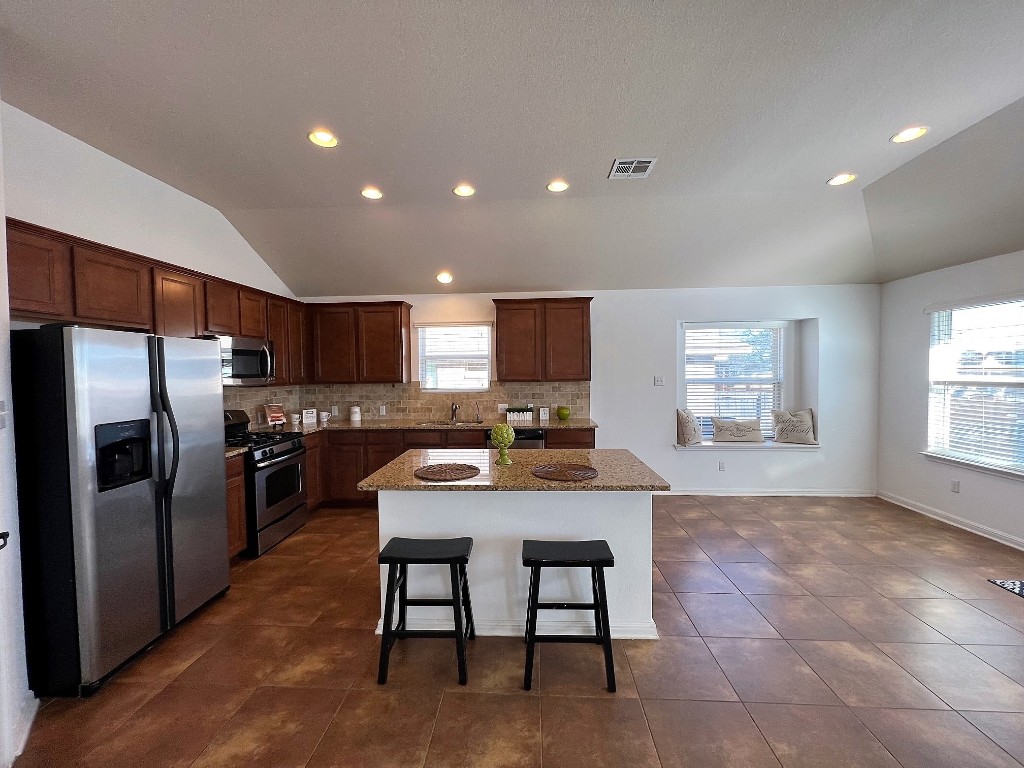 1711 Hidden Springs Path Round Rock, TX 78665 - Photo 11 of 39 a kitchen with stainless steel appliances granite countertop a stove a refrigerator a sink dishwasher with a dining table and chairs