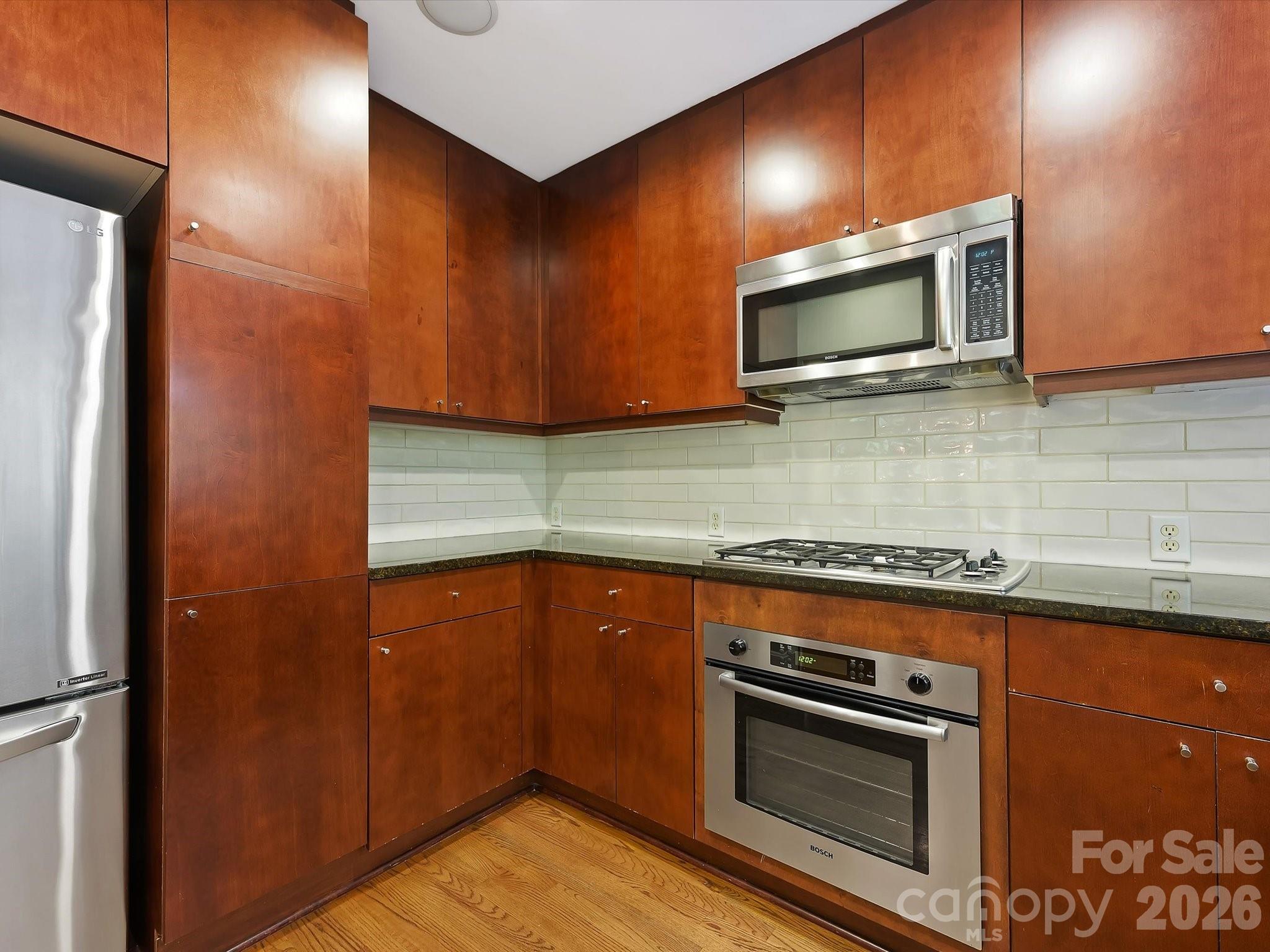 420 Queens Road Charlotte, NC 28207 - Photo 16 of 35 a kitchen with stainless steel appliances wooden cabinets and a stove top oven