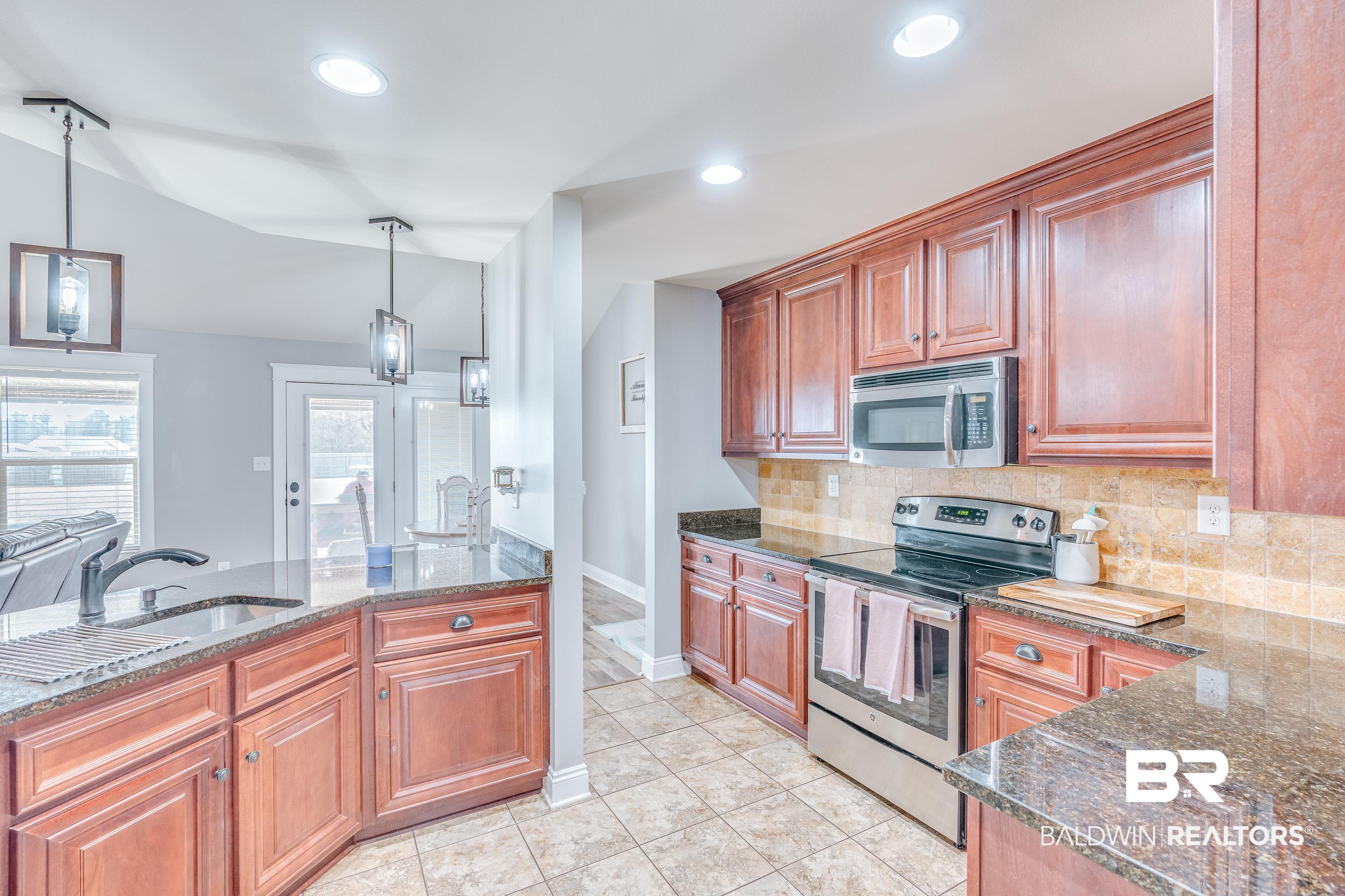 13235 Tom Gaston Road Mobile, AL 36695 - Photo 12 of 43 Kitchen featuring stainless steel appliances, sink, pendant lighting, and dark stone counters
