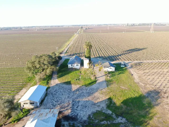 a view of a white house with a yard and potted plants