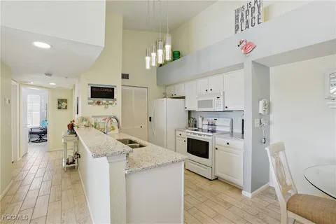 a kitchen that has a lot of white cabinets and stainless steel appliances