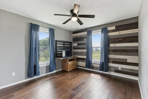 a view of empty room with wooden floor and window