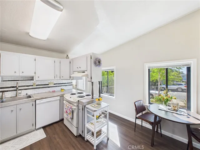 a kitchen that has a lot of cabinets in it with stainless steel appliances granite countertop a stove a sink dishwasher and white cabinets with wooden floor