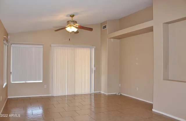 a view of an empty room with window and chandelier fan