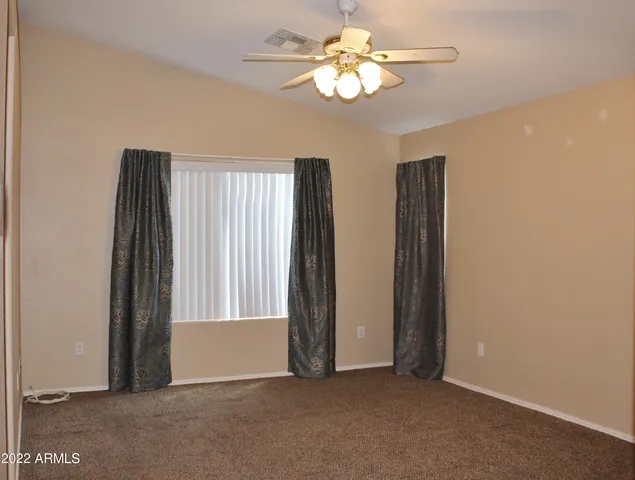 an empty room with windows and chandelier fan