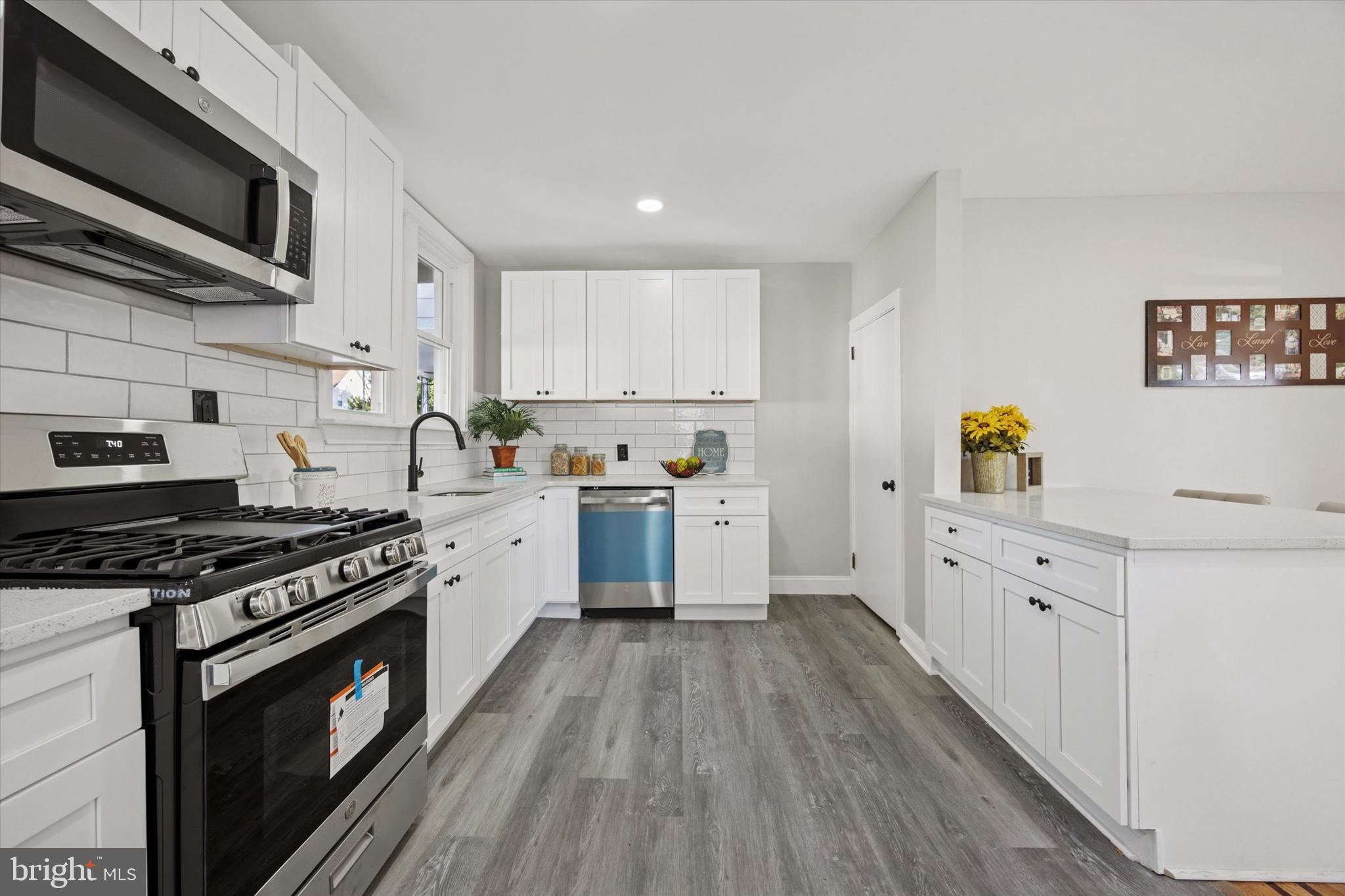 110 Sycamore Road Havertown, PA 19083 - Photo 6 of 25 a kitchen with granite countertop a stove top oven a sink dishwasher and white cabinets with wooden floor