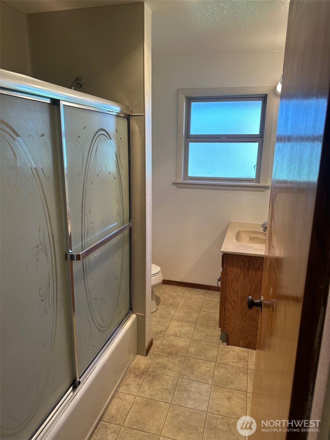 3504 Northeast 135th Street Seattle, WA 98125 - Photo 23 of 35 a view of a refrigerator in kitchen and an empty room in wooden floor