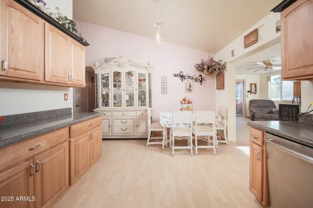 a large white kitchen with stainless steel appliances granite countertop a stove a sink dishwasher and white cabinets with wooden floor