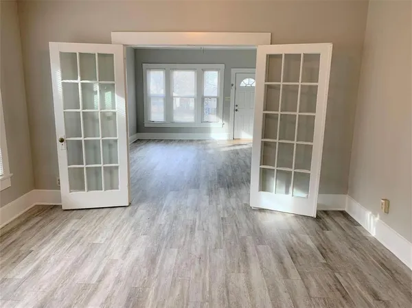 an empty room with wooden floor and windows