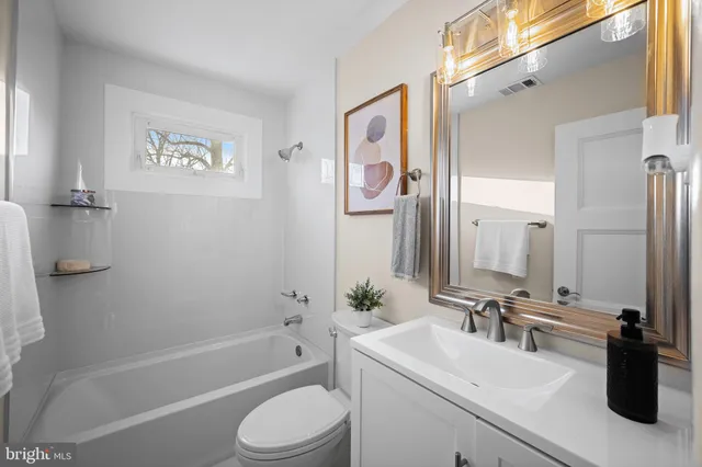 a bathroom with a bathtub shower sink vanity and toilet