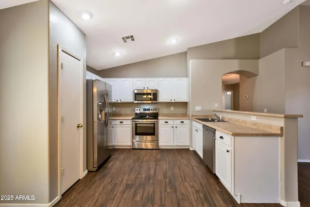 a kitchen with a white cabinets and wooden floor
