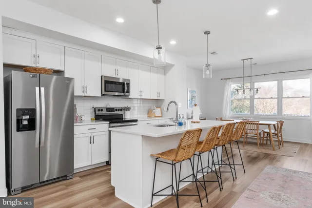 a kitchen with stainless steel appliances granite countertop a dining table chairs refrigerator and microwave