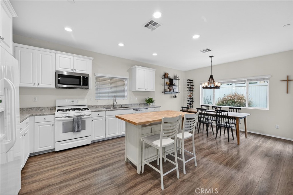 35462 Brown Galloway Lane Fallbrook, CA 92028 - Photo 11 of 63 a kitchen with stainless steel appliances granite countertop a stove top oven a sink dishwasher a dining table and chairs with wooden floor