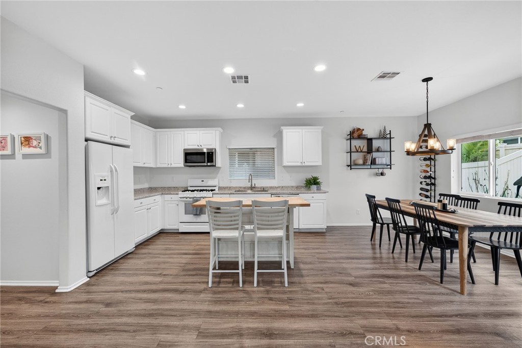 35462 Brown Galloway Lane Fallbrook, CA 92028 - Photo 12 of 63 a kitchen with stainless steel appliances kitchen island granite countertop a dining table chairs and white cabinets