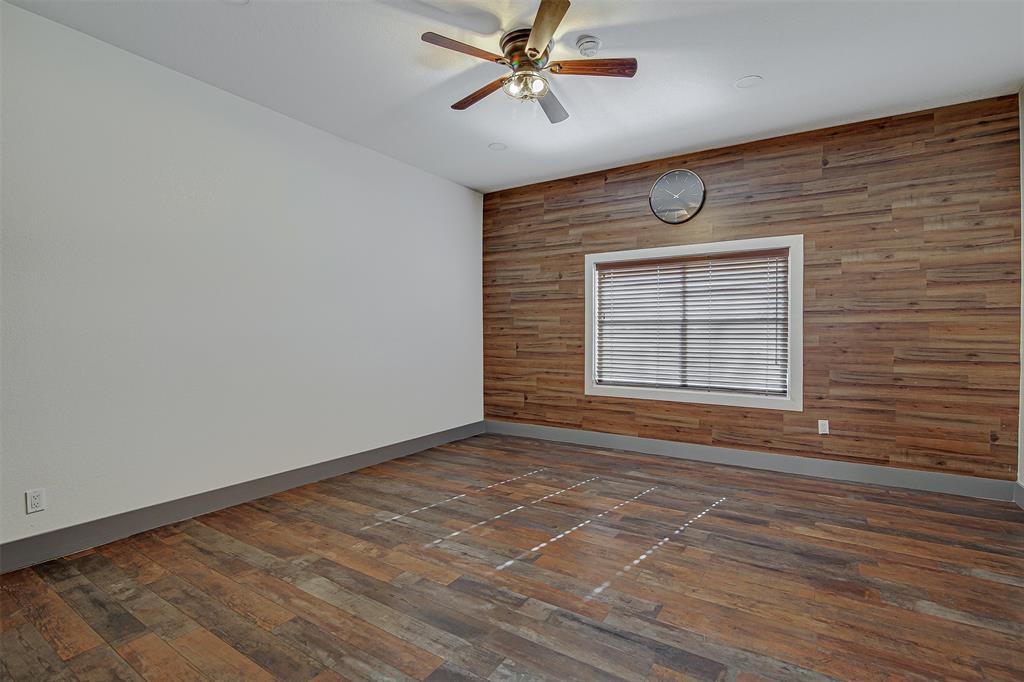 801 South Hampton Road Crowley, TX 76036 - Photo 4 of 26 Unfurnished room featuring wood walls, dark wood-style floors, ceiling fan, and an accent wall