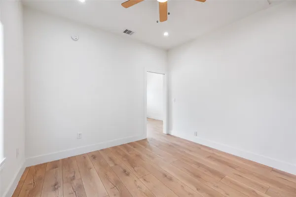 an empty room with wooden floor fan and window