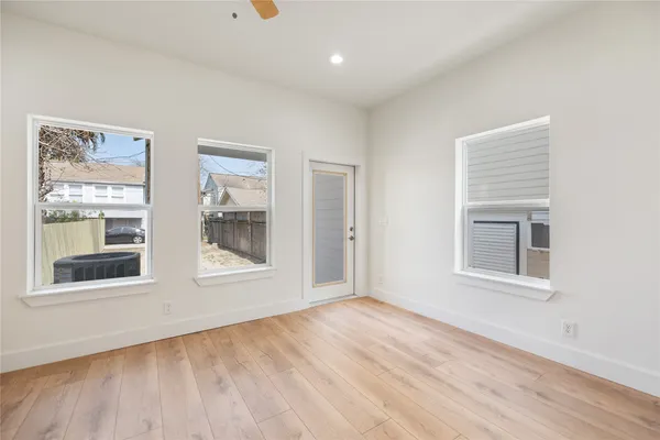 a view of an empty room with wooden floor and a window