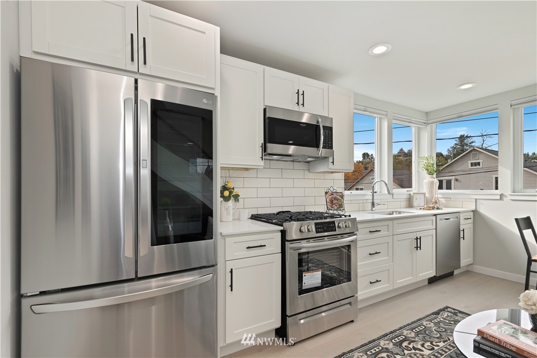 3638 36th Avenue South, Unit D Seattle, WA 98144 - Photo 3 of 30 a kitchen with white cabinets and stainless steel appliances