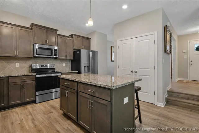 a kitchen with stainless steel appliances granite countertop a stove refrigerator sink and microwave